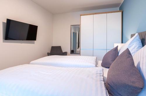 two beds in a hotel room with a tv at Lotusblume - 5 Sterne Ferienunterkunft mit möblierter Terrasse am Krakower See in Krakow am See
