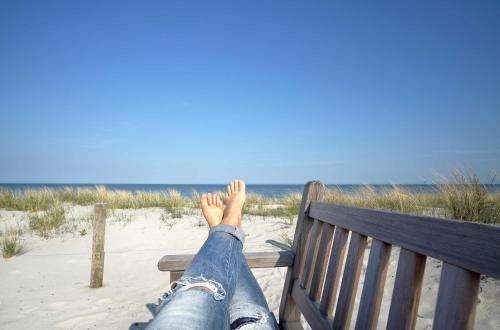 a person laying on a bench at the beach at Ferienwohnung Gänseblümchen Im Herzen der Halbinsel Fischland-Darß-Zingst in Wustrow