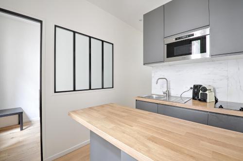 une cuisine avec un comptoir en bois et un évier dans l'établissement Ciseaux 3G - SAINT GERMAIN DES PRES - Superbe appartement, à Paris