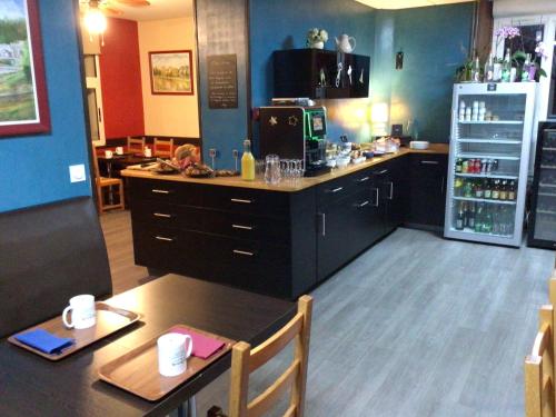 a kitchen with a table and a refrigerator at Hôtel Bellevue Bagnoles Normandie in Bagnoles de l'Orne