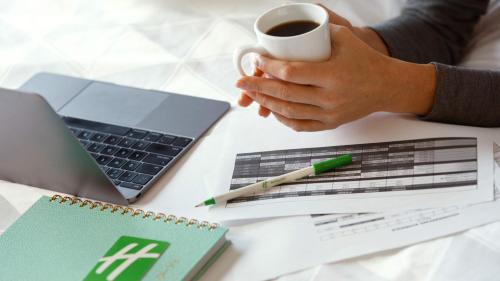 a person sitting at a desk with a cup of coffee and a laptop at Holiday Inn & Suites Makati by IHG in Manila