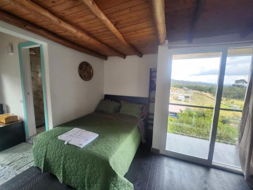 a bedroom with a green bed and a sliding glass door at Venado de Oro in Guatavita