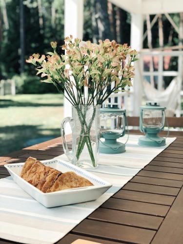 a table with a plate of bread and a vase with flowers at Villa Kungla in Käsmu
