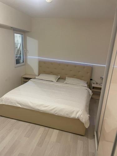 a bedroom with a bed with white sheets and a window at Strada calea unirii bloc 5 in Craiova
