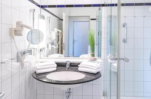 a white bathroom with a sink and a mirror at Strandhafer an der Seebrücke in Zingst