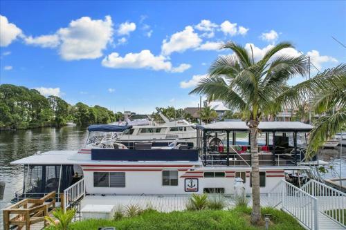 a boat docked in a marina with a palm tree at Unique Houseboat Rental in Merritt Island
