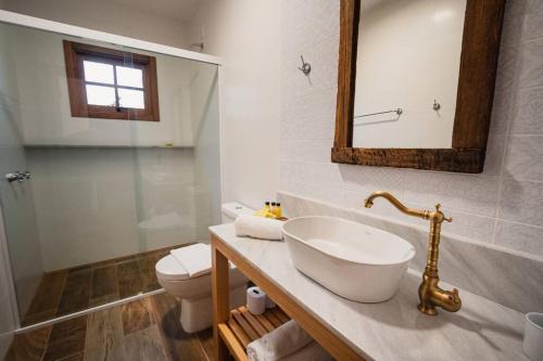 a bathroom with a sink and a toilet and a mirror at SÍTIO Canjerana em Gramado in Canela