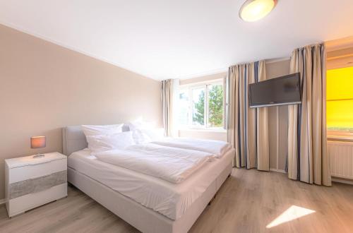 a bedroom with a white bed and a television at Kapitän Ed an der Seebrücke Zingst in Zingst