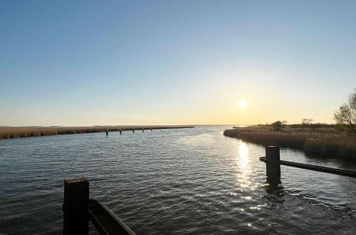 a view of a river with the sun in the distance at 5 Sterne Ferienhaus Ostseetraum - 50m zum Strand - Ladestation für E-Auto in Fuhlendorf