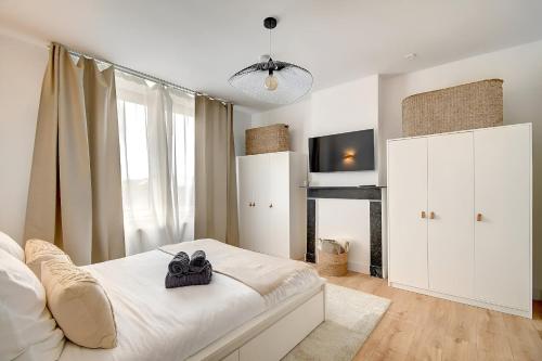 a white bedroom with a bed with shoes on it at - Le Cocoune - Cosy & Cute Flat in Liège