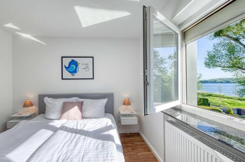 a bedroom with a bed and a large window at Ferienhaus Eddi am Tiefwarensee in Waren