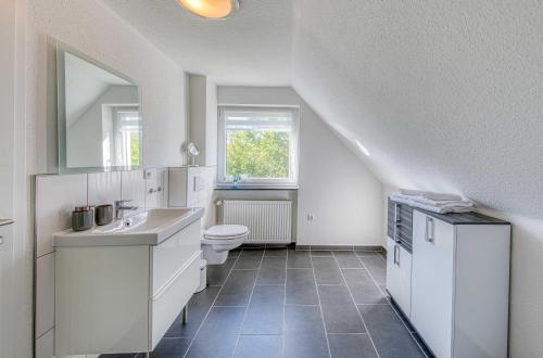 a white bathroom with a toilet and a sink at Ferienhaus Eddi am Tiefwarensee in Waren