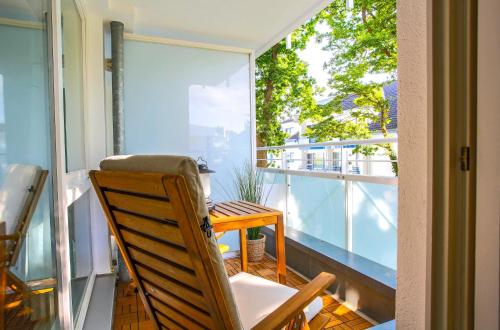 a balcony with a wooden table and a chair at Meereswoge Zingst in Zingst