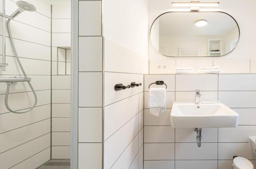 a white bathroom with a sink and a mirror at Ferienhaus "Bunter Fisch" - direkt am Deich, Strandübergang 19 in Wustrow