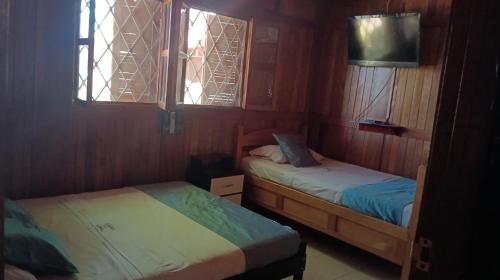 two beds in a small room with two windows at Chalet Completo para Familias Condominio Campestre Privado con Piscinas, wifi, AC in Santa Marta