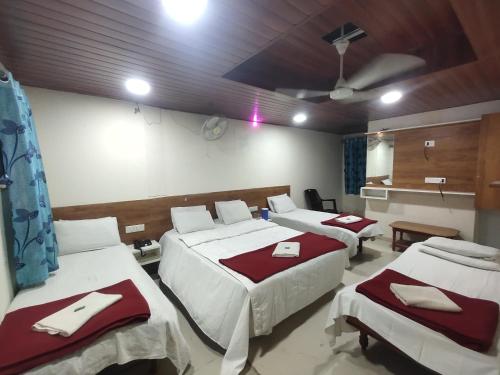a room with three beds with red and white sheets at Hotel yogeshwer in Mehsāna