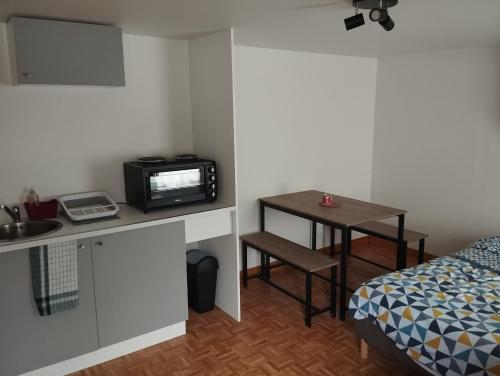 Cette petite chambre comprend un lit et une table avec un four micro-ondes. dans l'établissement Havre de paix, à Val-Fouzon