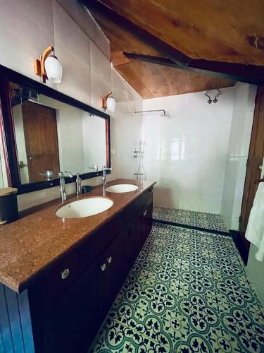 a bathroom with two sinks and a large mirror at Stumpfields in Ooty