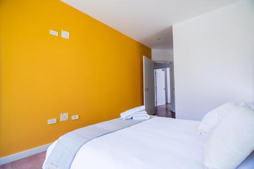 a bedroom with a white bed and an orange wall at Arezzo Forest View in Quito