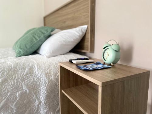 a bed with a wooden night stand with a clock on it at Loft a 3 min del mar in Veracruz