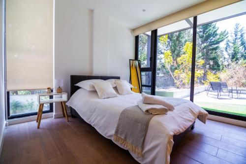 a bedroom with a large bed and large windows at Arezzo Forest View in Quito