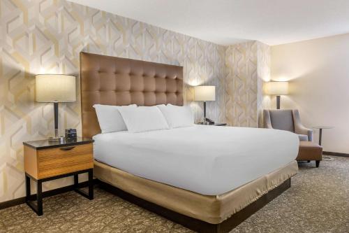 a bedroom with a large white bed and a chair at Drury Inn & Suites St. Louis-Southwest in Peerless Park