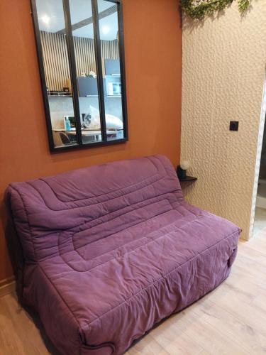 - un lit violet dans une chambre avec un miroir dans l'établissement Studette, au Mans