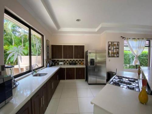a kitchen with stainless steel appliances and a large window at Exclusive house in Tambor golf club and private pool in Puntarenas