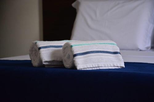 a stack of towels sitting on top of a bed at POUSADA CANTINHO DA Beth in Caravellas