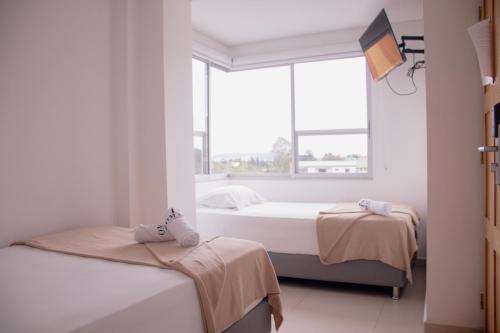 two beds in a room with a window at Hotel Omaga El peñol- Guatape in El Peñol
