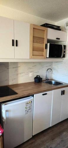 La cuisine est équipée d'un réfrigérateur blanc et d'un four micro-ondes. dans l'établissement Résidence Vanoise - VAL THORENS STUDIO 2 PERSONNES AVEC VUE DOMINANTE SUR CARON MAE-7803, à Val Thorens