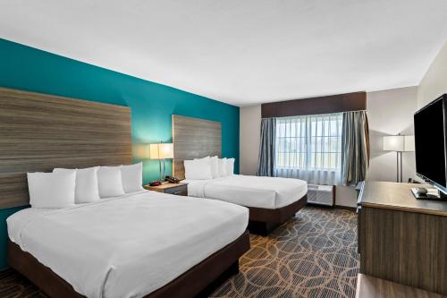 a hotel room with two beds and a flat screen tv at Best Western Presidential Hotel & Suites in Pine Bluff