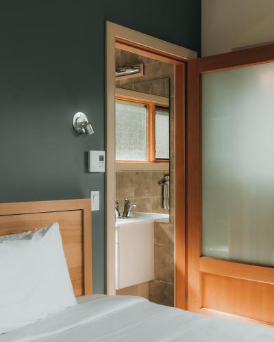 a bedroom with a bed and a bathroom with a sink at The Sentinel in Kaslo