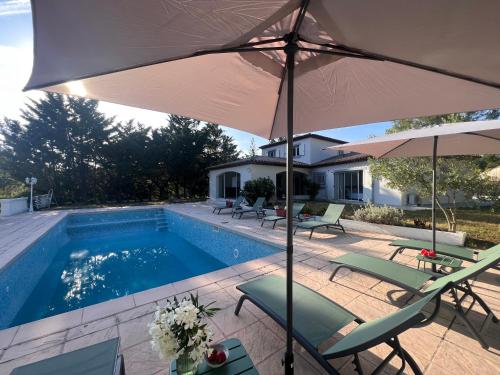 une piscine avec des chaises et des parasols ainsi qu'une maison dans l'établissement Douce Provence, à Saint-Paul-en-Forêt