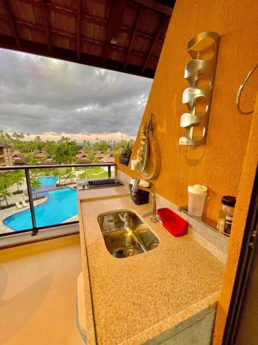 a kitchen with a sink and a view of a pool at Flats e apartamentos Eco resort Praia dos Carneiros in Tamandaré
