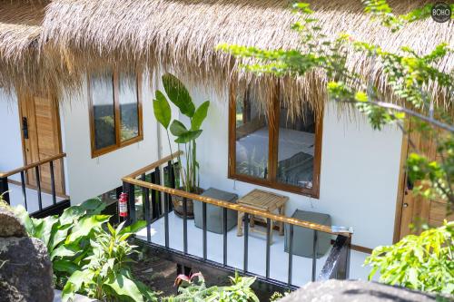 a house with a thatched roof and a balcony at BOHO Boutique Bungalows in Baan Tai