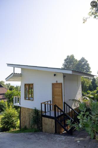 a small white house with a porch and a door at BOHO Boutique Bungalows in Baan Tai