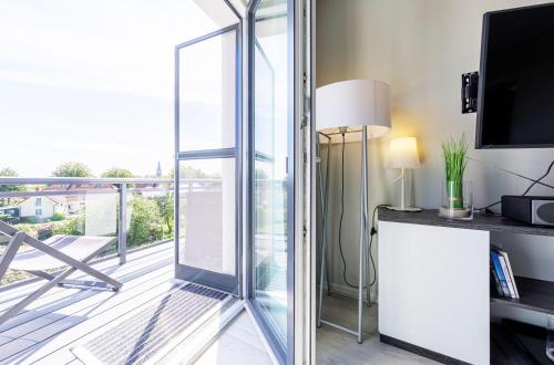 a room with a balcony with a sliding glass door at Boddenperle - 5-Sterne-Ferienwohnung mit Ostbalkon, 2 Bädern & Strandhaus-Charme in Wustrow
