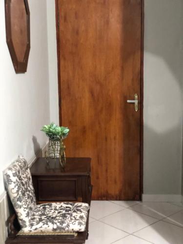a chair sitting next to a wooden door at Apartamentos Mãe Aparecida do Norte in Aparecida