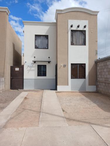 ein weißes Haus mit zwei Fenstern und einer Tür in der Unterkunft Vivienda completa 2 plantas, y privada con acceso controlado in Hermosillo