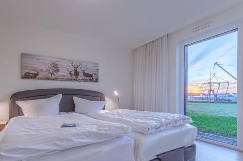 a bedroom with a large bed with a large window at MüritzKieker - Apartment in der Hafenresidenz mit Kamin & Wellness in Waren