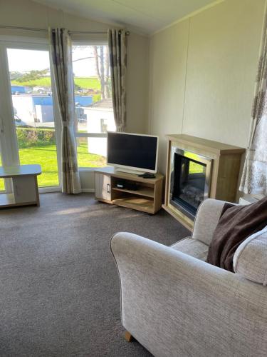a living room with a couch and a television at Rubys Retreat - 6 Berth Caravan in Newquay, Cornwall in Newquay