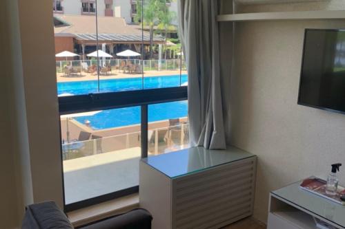 a hotel room with a view of a pool through a window at Flat no Life Resort a Beira Lago in Brasilia