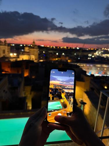 a person taking a picture of a city with a cell phone at Authentic Maltese Boutique Holiday Home with Rooftop Pool - Moon Townhouse in Cospicua