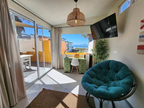 a living room with a blue chair and a television at CASA LUCIA - BEACHFRONT HOUSE in Ensenada