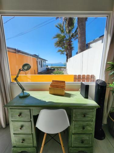 a desk with a lamp and a chair in front of a window at CASA LUCIA - BEACHFRONT HOUSE in Ensenada
