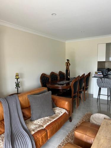 a living room with a leather couch and a table at Guesthouse koonawarra in Dapto