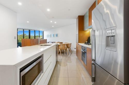 a kitchen with white appliances and a dining room at Cotton Beach 53 by Kingscliff Accommodation in Casuarina