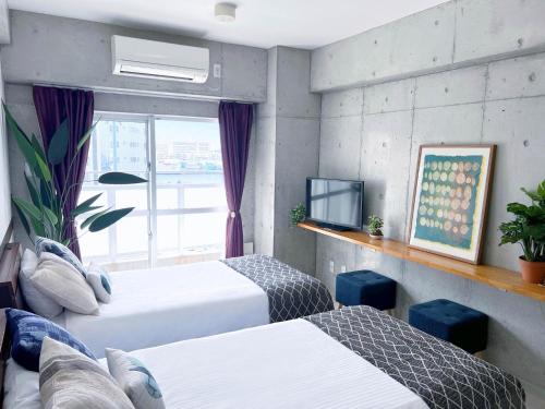a hotel room with two beds and a window at ALBERGO PINO Tomari - Vacation STAY 77963v in Naha
