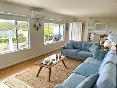 a living room with a blue couch and a table at 3 Beaches Cottage in Surf Beach